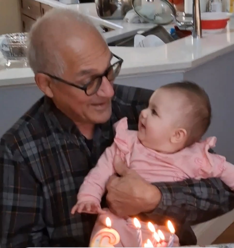 Pop holding his new grandbaby and smiling lovingly